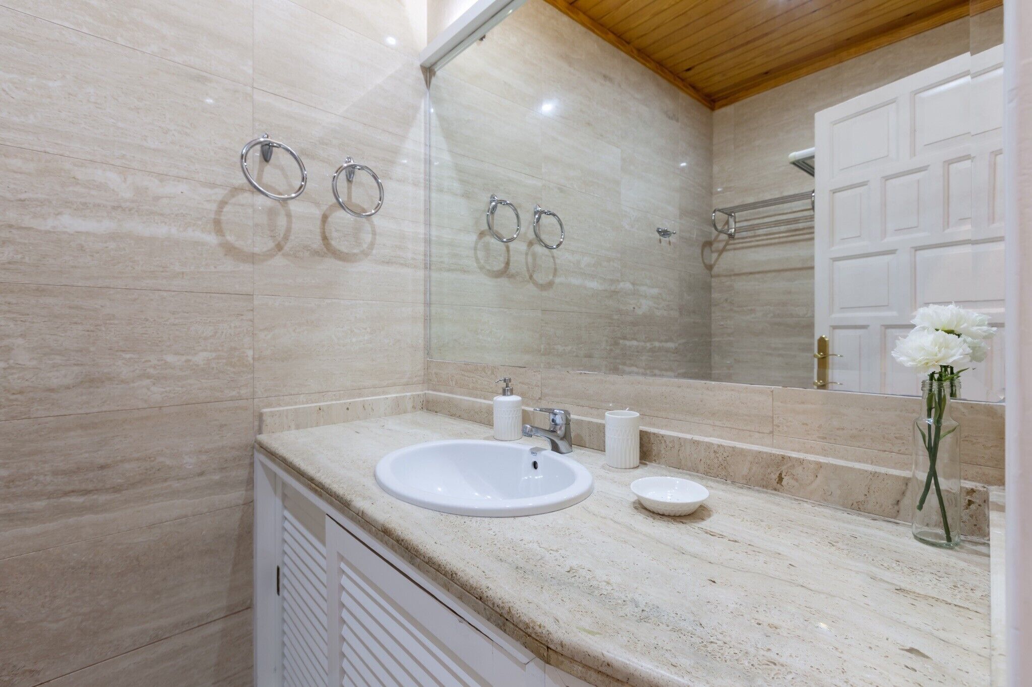A bathroom with a white sink, a mirror, and a shower area.