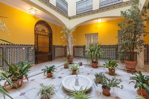 A courtyard with a fountain, potted plants, and a decorative gate. - City Centre Apartment with Balcony, Elevator and WiFi (Seville)