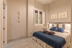 A bedroom with a bed, a nightstand, a window with curtains, and wall-mounted artwork. - City Centre Apartment with Balcony, Elevator and WiFi (Seville)