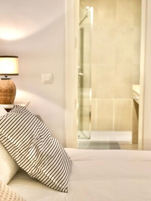 A hotel room with a bed, a bedside lamp, and a view of a bathroom with a shower. - Cozy and Quiet City Centre Apartment with WiFi (Seville)