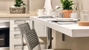 A modern kitchen with a white countertop, a stainless steel range hood, and a dining area with a chair and table set. - Cozy and Quiet City Centre Apartment with WiFi (Seville)