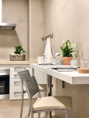 A modern kitchen with a white countertop, a stainless steel range hood, and a dining area with a chair and table set. - Cozy and Quiet City Centre Apartment with WiFi (Seville)