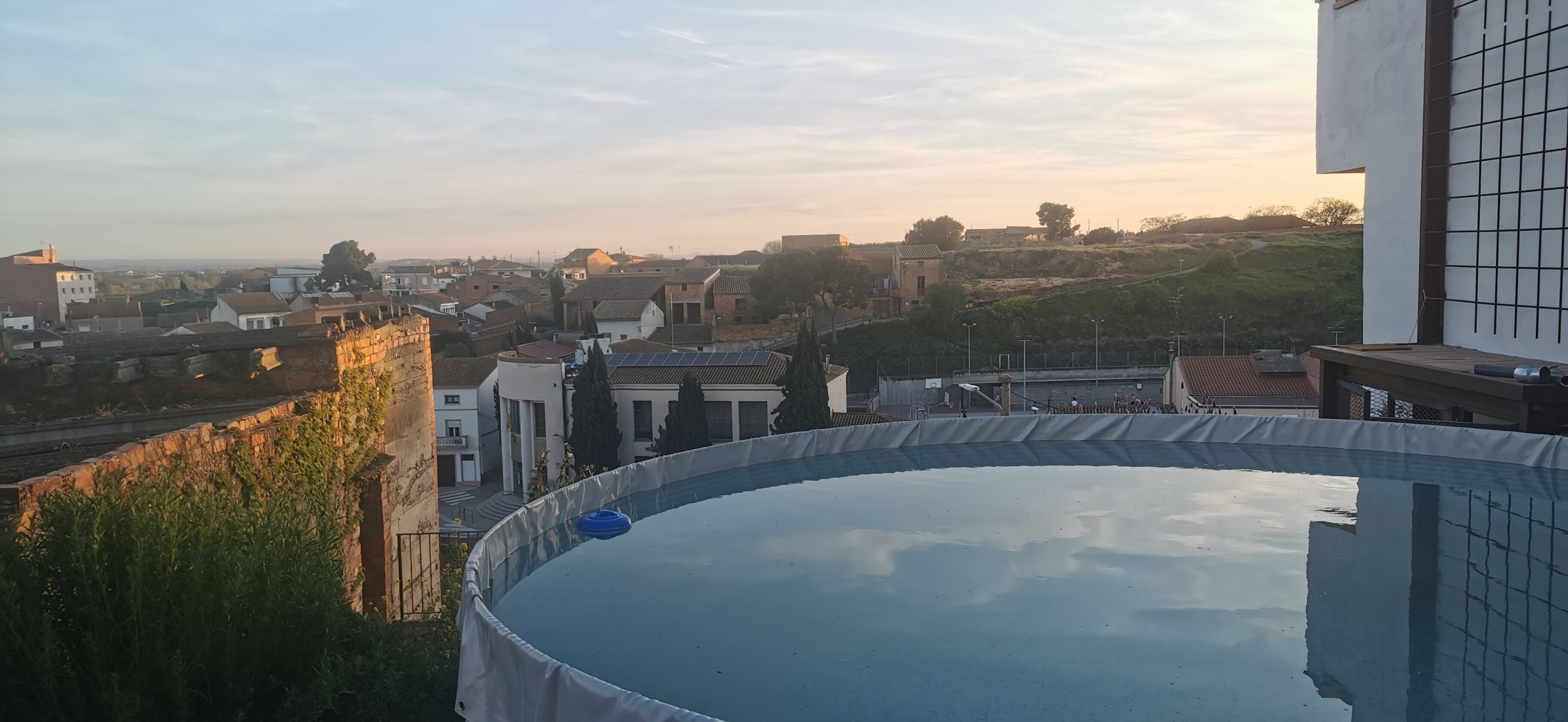 Une piscine avec vue sur un quartier résidentiel et une colline en arrière-plan.