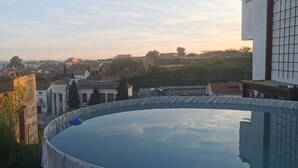 Uma piscina com vista para uma área residencial e uma colina ao fundo.