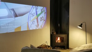 Uma tela de projeção exibindo um relógio com o texto 'ARTE France Sourdoreille Production' em um ambiente com lareira e abajur.