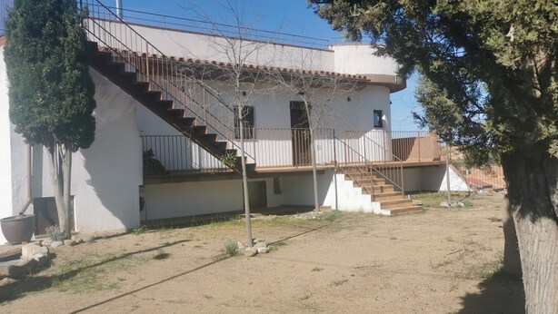 Um edifício de dois andares com uma escadaria que leva a uma varanda.