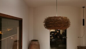 Um quarto com luminária pendente feita de materiais naturais, um barril de madeira e uma tomada na parede.
