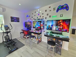A gaming room with multiple monitors, a treadmill, and a bar area. - Tranquil Retreat, Resort Pool, Sauna, Arcade (Lutz)
