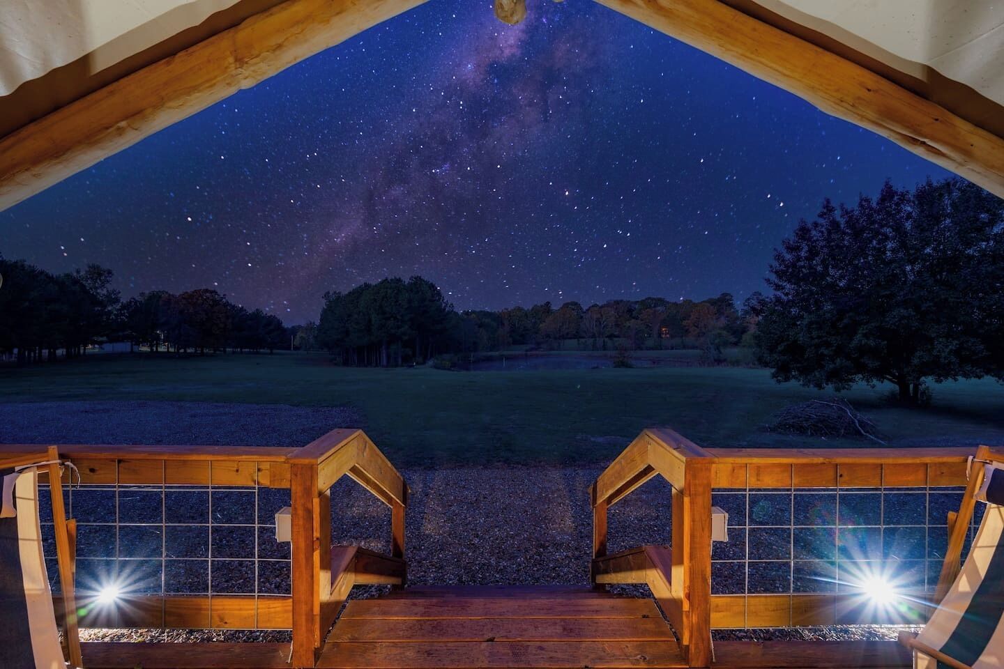 A wooden deck with a view of the night sky, including stars and the Milky Way.
