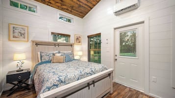 A bedroom with a bed, bedside tables, a door, and a window.