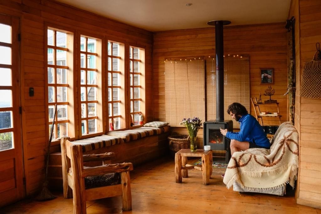 L’intérieur d’un chalet chaleureux, avec une grande cheminée en bois, un banc et un canapé.
