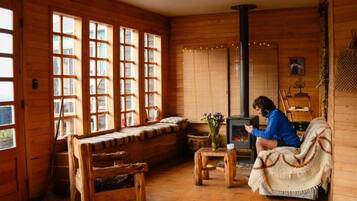 L’intérieur d’un chalet chaleureux, avec une grande cheminée en bois, un banc et un canapé.