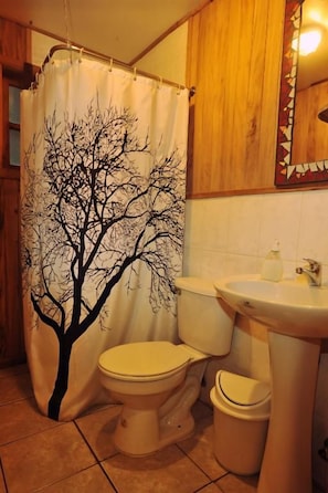 Un baño con inodoro, lavamanos y cortina de ducha con diseño de árbol.