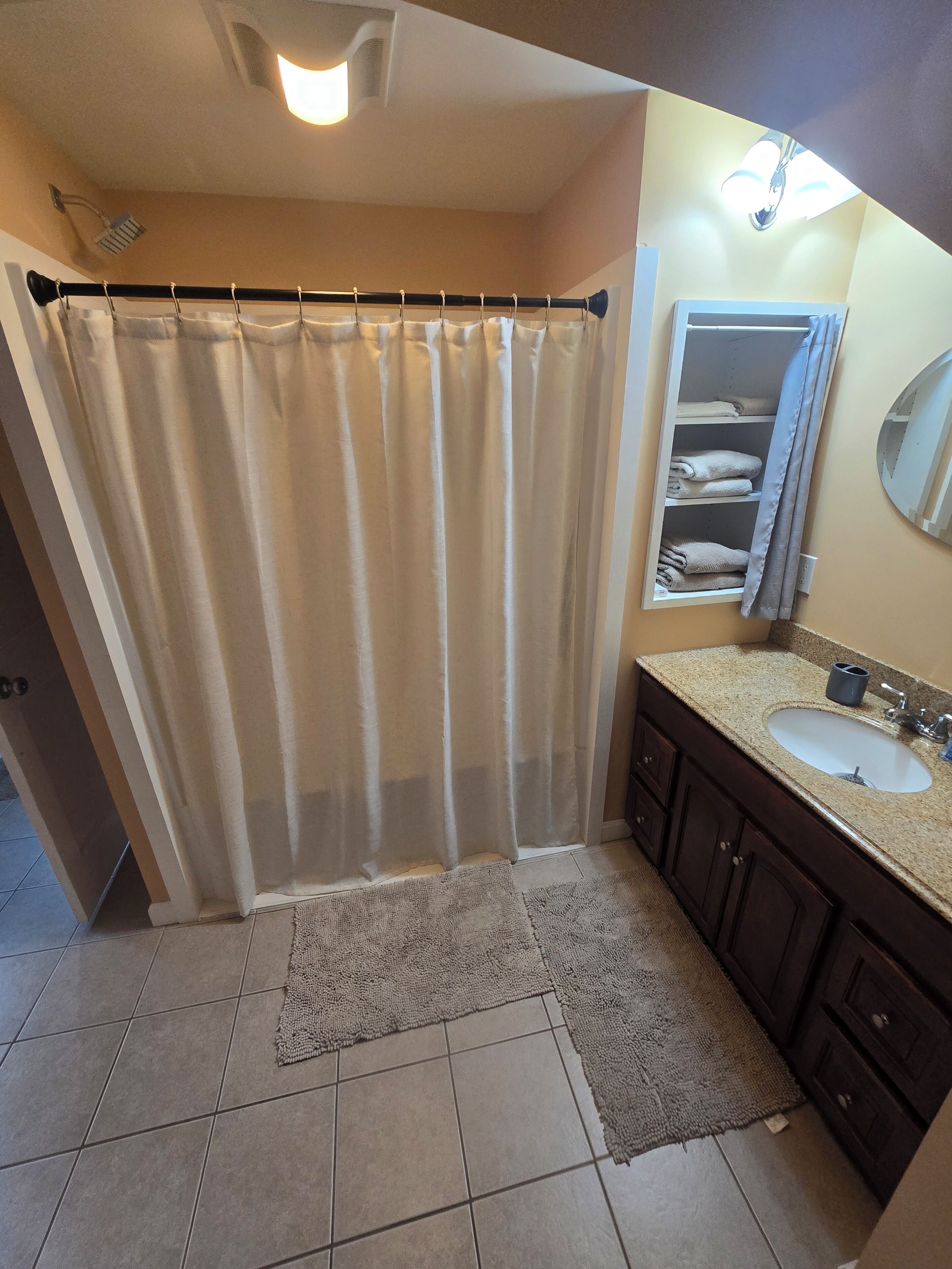 A bathroom with a shower curtain, a sink, a mirror, and a towel rack.