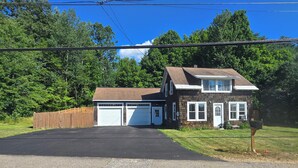 A two-story house with a garage, surrounded by a wooden fence and trees. - Lakes Region Family Getaway& Pet Friendly (Belmont)