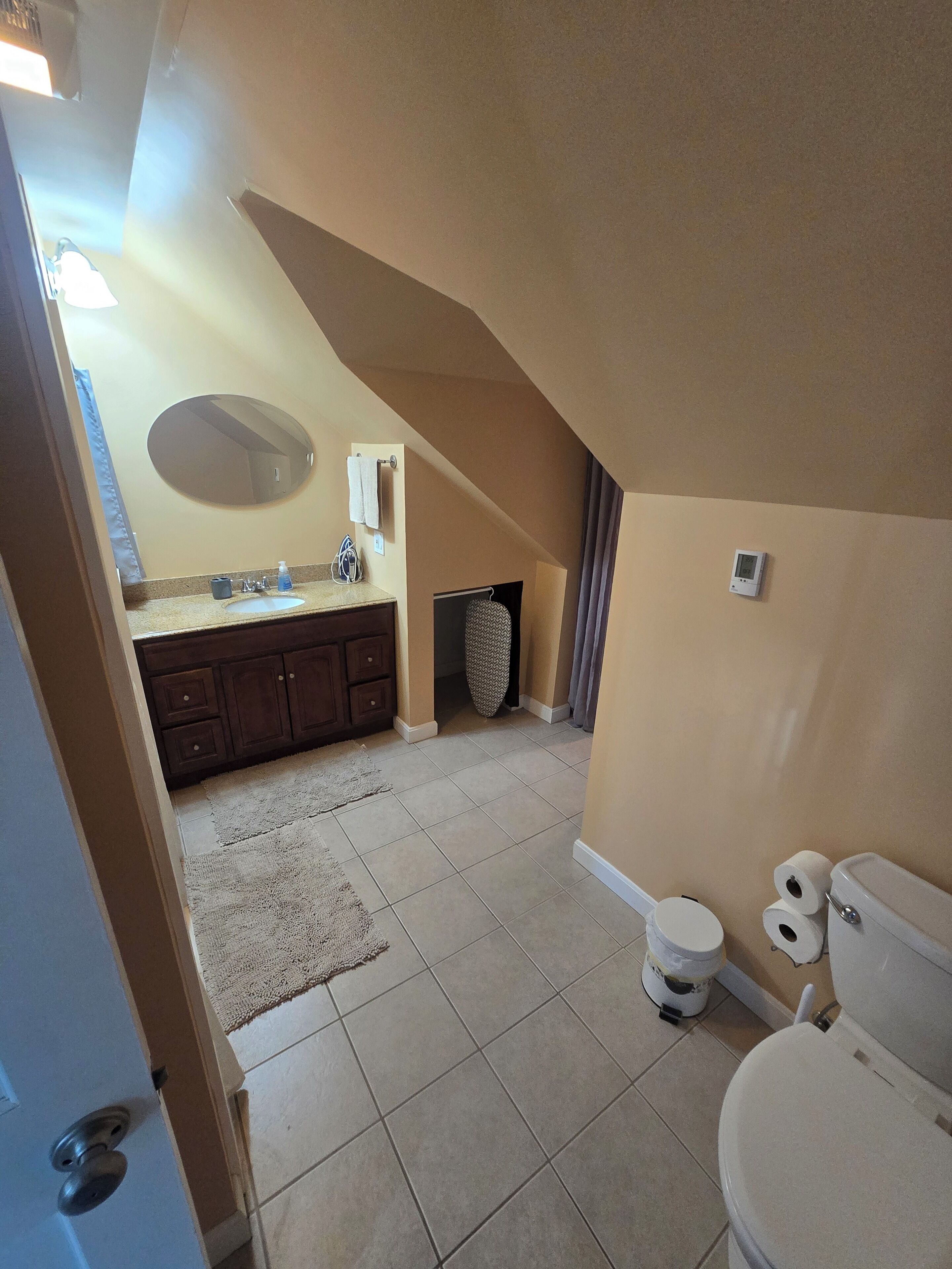 A bathroom with a sink, mirror, towel rack, toilet, and a shower area.