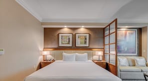 A hotel room with a large bed, two bedside lamps, a wooden headboard, and two framed artworks above the bed. - MGM Studio: Free Parking, Jacuzzi, Strip Views (Las Vegas)