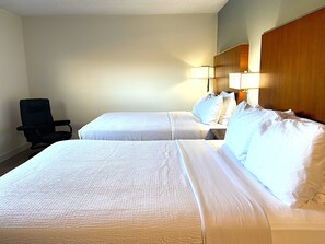Une chambre d’hôtel avec deux lits, une chaise et une table de chevet avec des lampes.