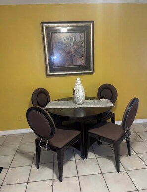 A dining table with four chairs, a vase, and a framed picture on the wall. - Cozy 2-bedroom house in pleasant Lauderhill with AC (Lauderhill)