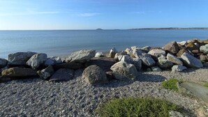 Una costa rocosa con mar en calma y cielo despejado.