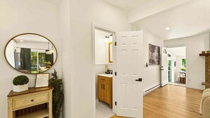 A spacious room with a wooden floor, a white door leading to a bathroom, a mirror with a gold frame, and a small potted plant on a dresser. - Unwind In Pocono Getaway W/Hot Tub & Game Room Near Kalahari, Camelback, Casino (Albrightsville)