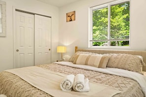 Un dormitorio con cama, una ventana con persianas, una puerta y una lámpara fijada a la pared.