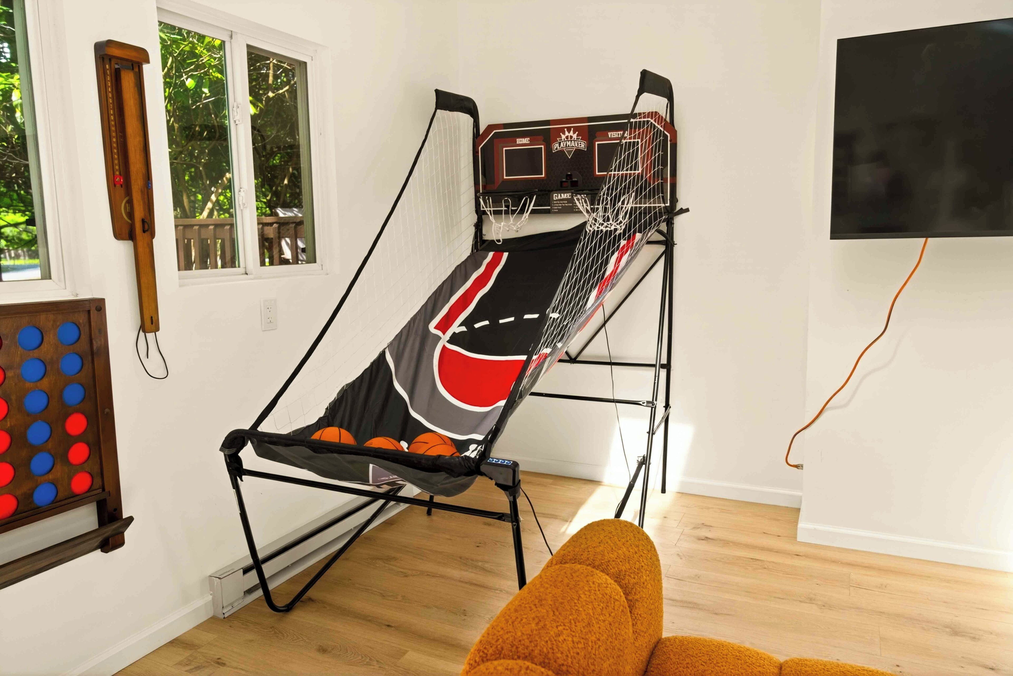A room with a basketball hoop, a television mounted on the wall, and a wooden floor.