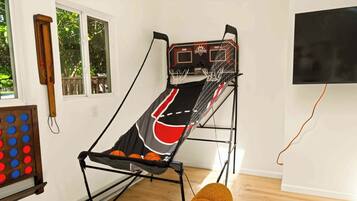 A room with a basketball hoop, a television mounted on the wall, and a wooden floor.