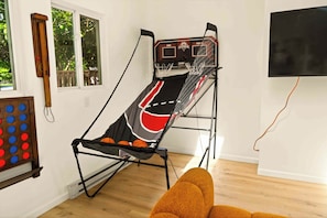 Una habitación con un aro de baloncesto, un televisor fijado a la pared y suelo de madera.