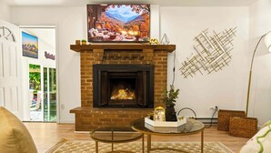 A living room with a fireplace, a sofa, a coffee table, and a painting above the fireplace. - Unwind In Pocono Getaway W/Hot Tub & Game Room Near Kalahari, Camelback, Casino (Albrightsville)