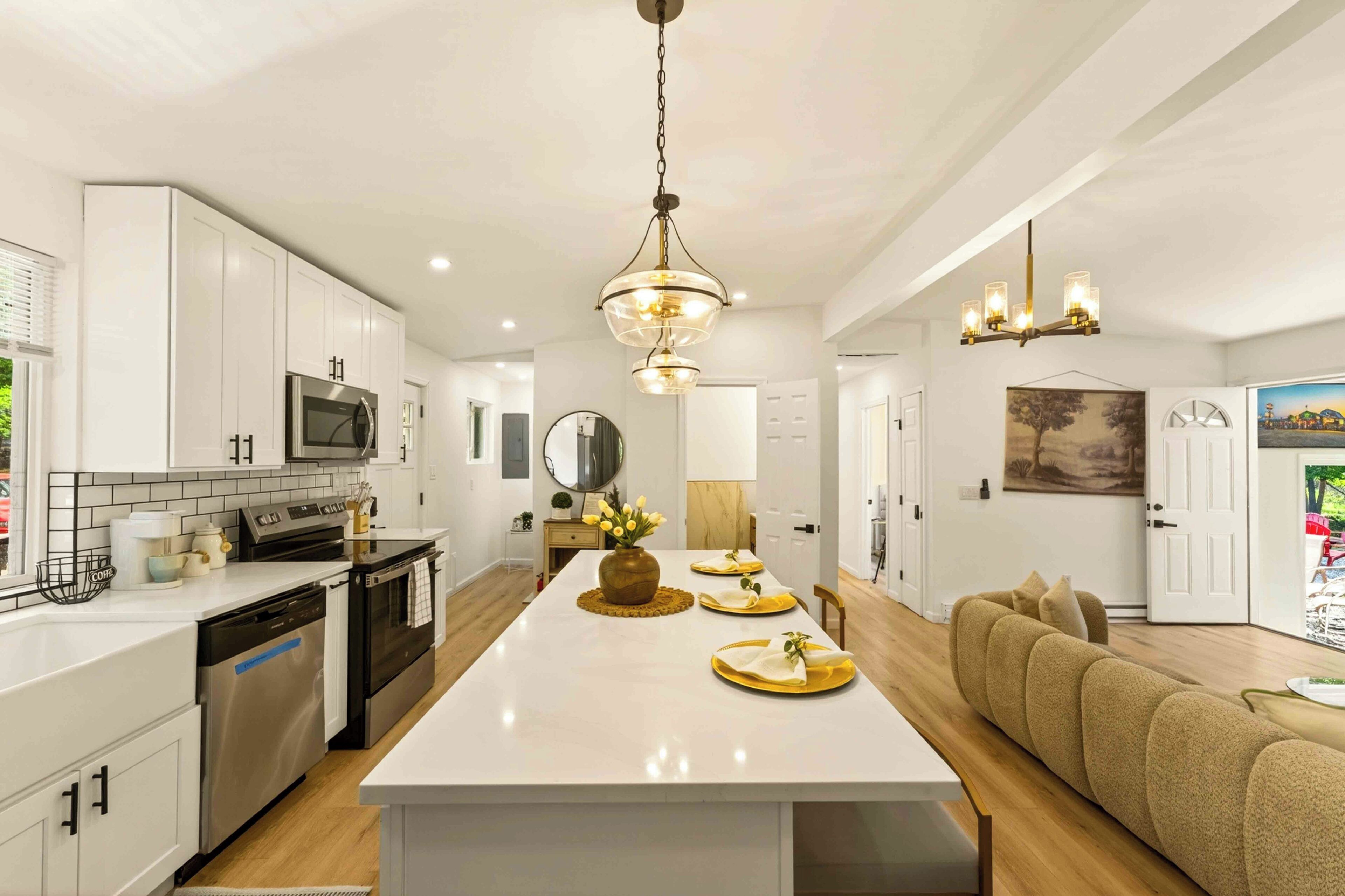 A modern kitchen with white cabinetry, stainless steel appliances, and a central island.
