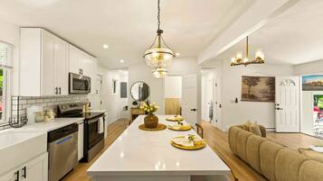 A modern kitchen with white cabinetry, stainless steel appliances, and a central island.