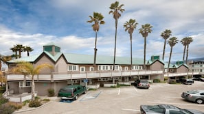 A motel with a parking lot, a covered walkway, and palm trees.