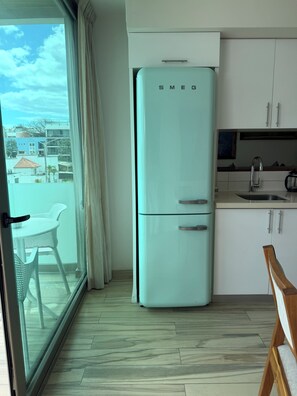 Une cuisine moderne dotée d’un réfrigérateur encastré, d’un évier et d’un coin repas avec une table et des chaises.