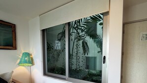 Ein Zimmer mit großem Fenster, Holzboden, gemustertem Teppich, einer Couch und einer Lampe.