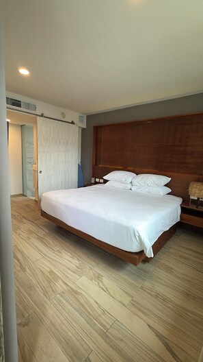 A hotel room with a large bed, wooden headboard, and a wooden floor. - LUXURY Apartment. 1 block from 5th Avenue (Playa del Carmen)