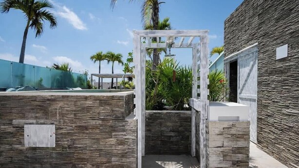 Ein moderner Außenbereich mit einer Holz-Pergola, Steinmauern und einem Pool.