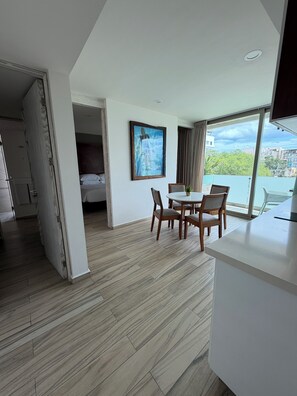 A modern hotel room with a dining area, a bed, and a large window offering a city view. - LUXURY Apartment. 1 block from 5th Avenue (Playa del Carmen)