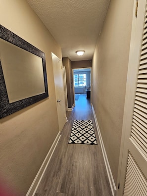 A hallway with a patterned rug, a door on the left, and a window at the end. - Stay in the Heart of Downtown Atlanta Sleeps 4 Perfect for Getaways. (Atlanta)