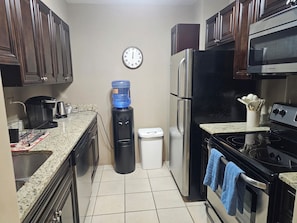 A kitchen with a water dispenser, a clock, a refrigerator, and a stove. - Stay in the Heart of Downtown Atlanta Sleeps 4 Perfect for Getaways. (Atlanta)
