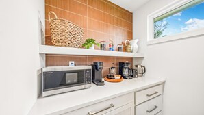 Eine moderne Küche mit Mikrowelle, Kaffeemaschine und Regalen mit Geschirr.