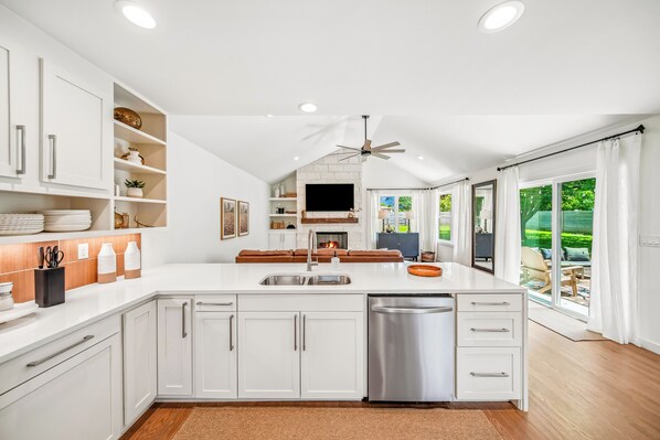 Una cocina moderna con armarios blancos, lavavajillas integrado y una isla grande con fregadero.