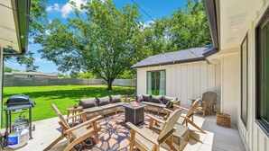 Ein Außenbereich mit Terrasse, Feuerstelle, Sitzgelegenheiten und Grill.