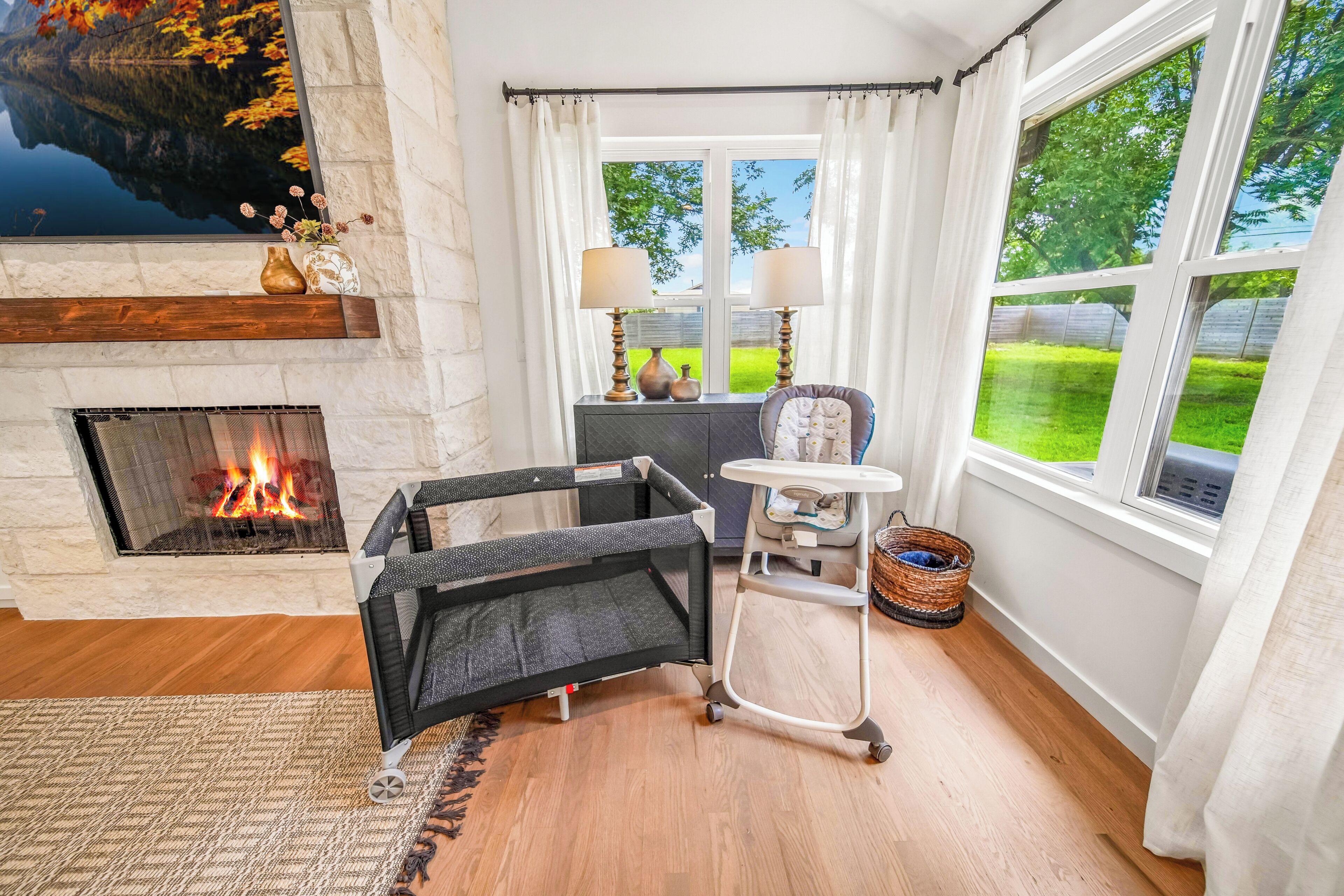 A cozy room with a fireplace, a baby changing station, and a view of a green landscape.