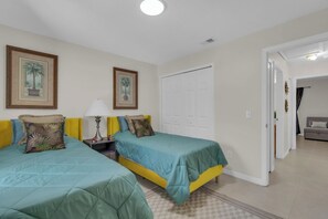 A bedroom with two beds, a nightstand, a lamp, and a door leading to another room. - The Pinecone Retreat / Pool Home / Near Disney (Davenport)
