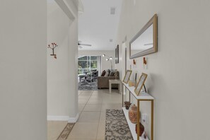 A hallway leading to a living room with a sofa, coffee table, and decorative items. - The Pinecone Retreat / Pool Home / Near Disney (Davenport)