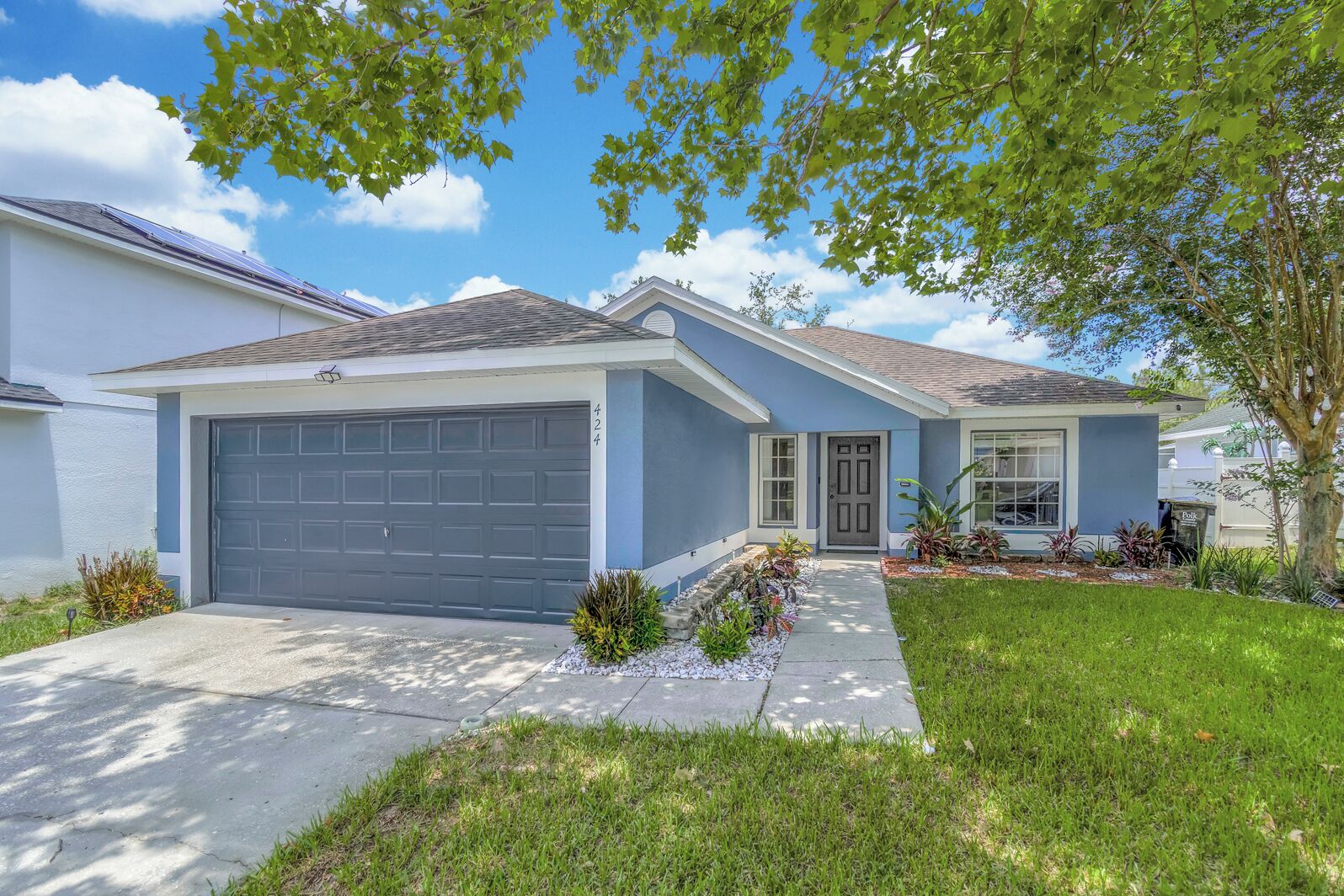 A residential house with a garage, a front porch, and a well-maintained lawn.