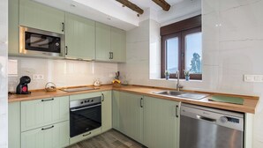A kitchen with light green cabinets, a built-in oven, a microwave, a sink, and a dishwasher. - Casa Rural Museo del Trovo y Aguardiente Murtas by Ruralidays (Granada)