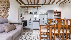 A compact living space with a kitchenette, a dining area with wooden chairs, and a sofa. - Casa Rural Museo del Trovo y Aguardiente Murtas by Ruralidays (Granada)