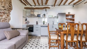 Ein kompakter Wohnraum mit Küchenzeile, einer Essecke mit Holzstühlen und einem Sofa.